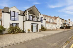 A residential street with modern houses, a paved sidewalk, and a clear sky. - Seaside House - North East Escapes (Beadnell)