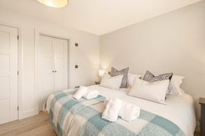 A bedroom with a bed, pillows, a blanket, and a nightstand. - Seaside House - North East Escapes (Beadnell)