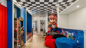 Une pièce avec un plafond à carreaux, une statue de Mario et une console de jeux PlayStation 2.