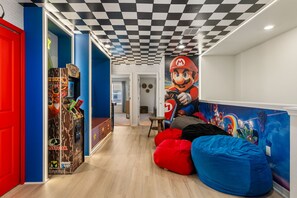 Ein Zimmer mit kariertem Himmel, einer Mario-Statue und einer PlayStation 2 Spielekonsole.