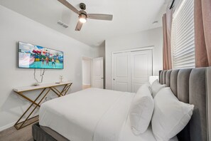 A bedroom with a bed, a desk, a television, a ceiling fan, and a door. - 4254 Lana Avenue (Davenport)