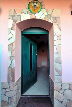 A doorway with a stone archway and a green door, leading into a room with a tiled floor. - A villa with a view of the sea, surrounded by nature, tranquility, and relaxation in the heart of Sicily. (Santo Stefano)