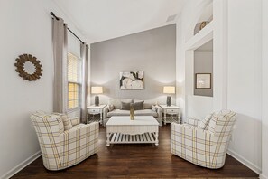A room with a sofa set, a coffee table, two bedside tables with lamps, a wall art piece, and a mirror. - 4036 Oakrise Loop (Davenport)