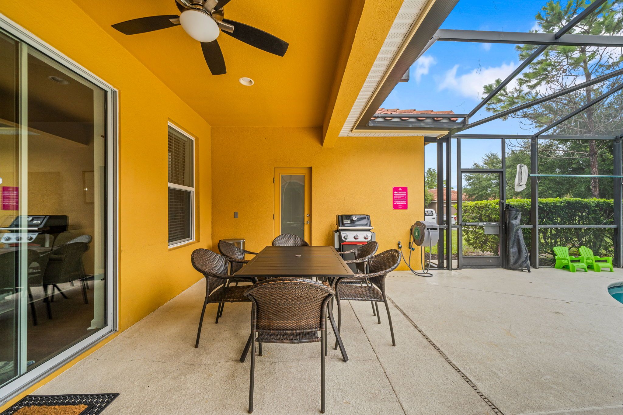 An outdoor patio with a table and chairs, a ceiling fan, and a grill.