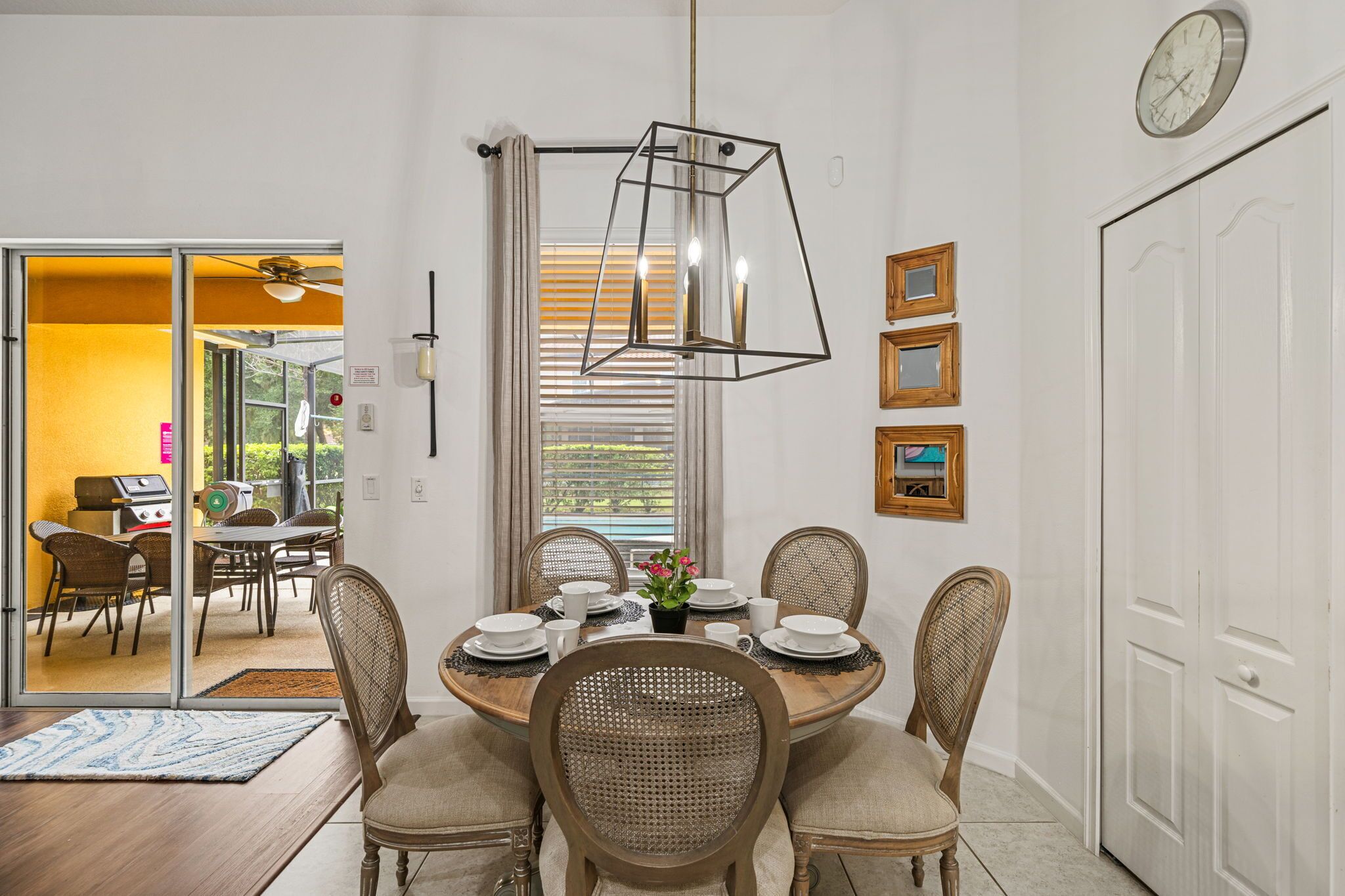 A dining area with a round table, six chairs, and a hanging light fixture.