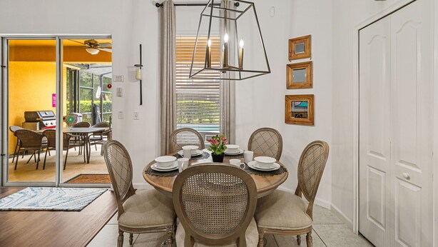 Un coin repas avec une table ronde, six chaises et un luminaire suspendu.