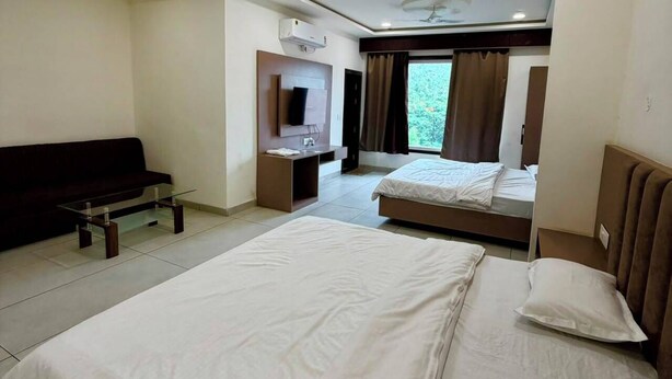 A hotel room with a bed, a sofa, a desk, and a television.