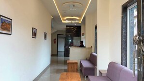 Un vestíbulo de hotel con recepción, zona de estar y un banco de madera.