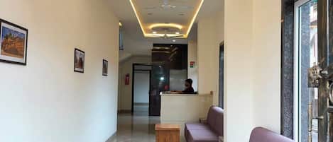 A hotel lobby with a reception desk, seating area, and a wooden bench.