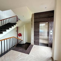 Un interior moderno con escalera, ascensor y suelo de mármol.