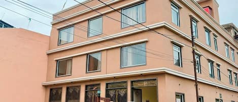 A multi-story hotel with a flat facade, large windows, and a gated entrance.