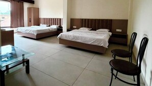 Habitación de hotel con dos camas, una mesa de vidrio y una silla.