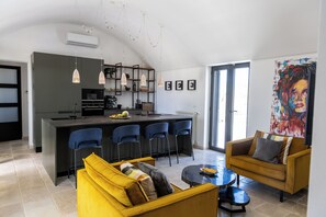 Cozinha moderna com ilha central, bancada para refeições e uma grande janela.