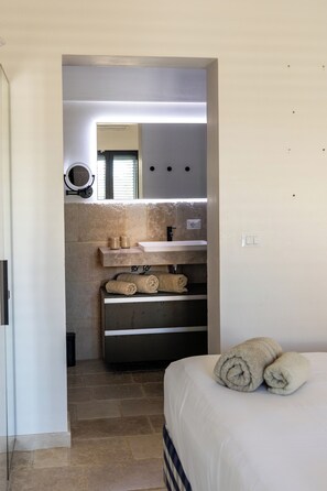 A narrow hallway leading to a bathroom with a sink, mirror, and towel storage. - Stunning Villa Teodoro (Ostuni)