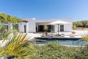 A modern house with a swimming pool, outdoor seating, and a garden. - Stunning Villa Teodoro (Ostuni)