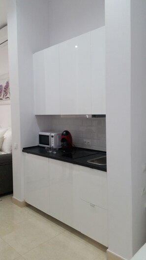 A kitchen with white cabinets, a black countertop, a microwave, and a red kettle. - Panther Home Luxury Dreams (Casco Historico)