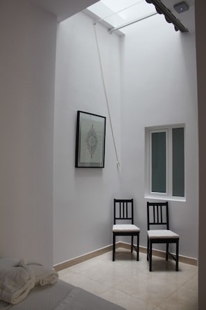 Una habitación con tragaluz, una obra de arte enmarcada, dos sillas y una ventana.