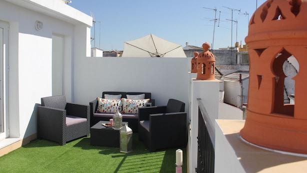 Terraza en la azotea con un conjunto de sofás, una mesita y objetos decorativos.