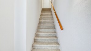 Uma escada com corrimão de madeira que leva a uma porta branca no topo.