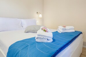 Ein Hotelzimmer mit einem Bett, Kissen, einer blauen Bettdecke und ordentlich gefalteten Handtüchern mit Blumen.