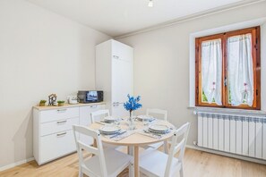 Eine kompakte Küche mit Mikrowelle, einem kleinen Kühlschrank und einem Esstisch für zwei Personen mit Stühlen.