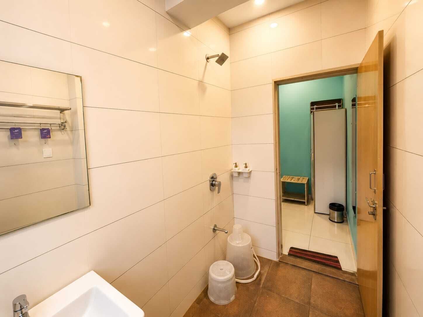 Une salle de bain moderne avec un lavabo blanc, une douche et des toilettes séparées par une paroi de verre.