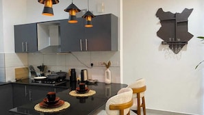 Una cocina moderna con una isla central, iluminación colgante y un adorno en la pared.