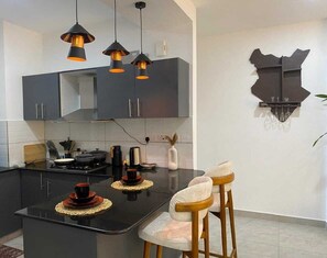 Una cocina moderna con una isla central, iluminación colgante y un adorno en la pared.