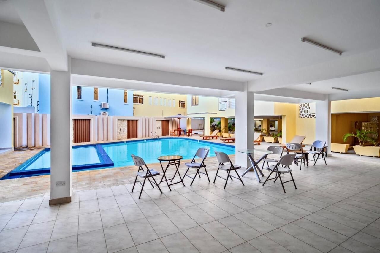A pool area with lounge chairs and a covered seating area.