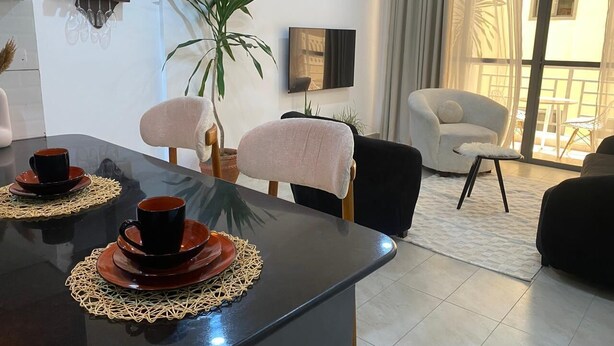 Una sala de estar moderna con comedor, una planta grande en maceta y un sofá.