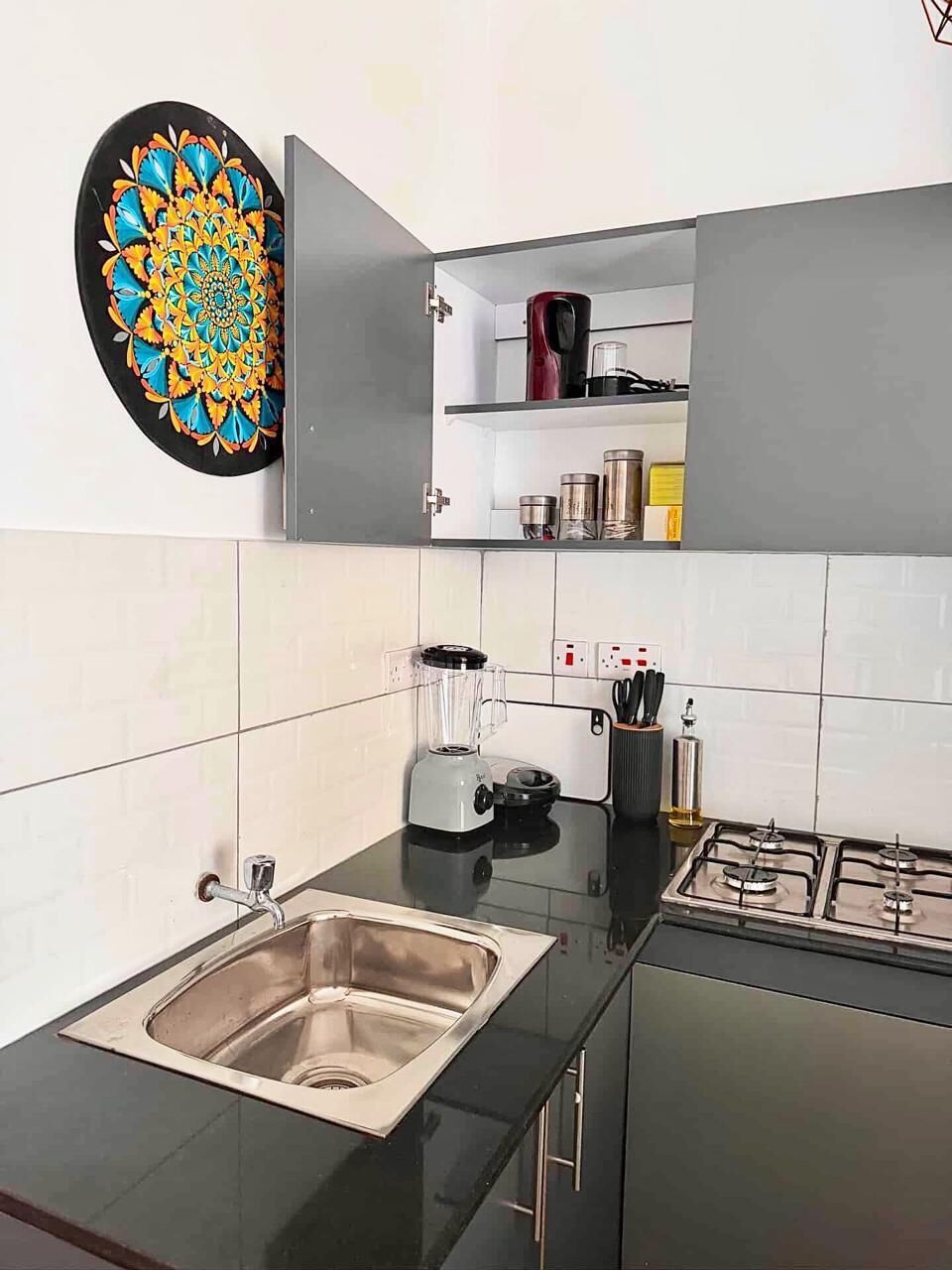 A modern kitchen with a stainless steel sink, a gas stove, a blender, and a microwave.