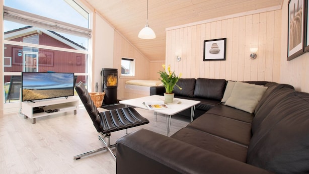 Ein modernes Wohnzimmer mit großem Fernseher, Kamin, Sofa und Esstisch.