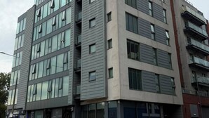 Ein mehrstöckiges Gebäude mit moderner Architektur, gekennzeichnet durch große Fenster und ein Flachdach.