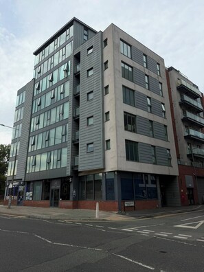 A multi-story building with a modern architectural design, featuring large windows and a flat roof. - Elegant 2-Bed w/ Balcony | City Centre (Liverpool)