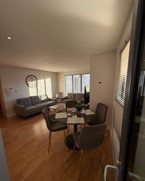 A modern living room with a sofa, a dining table with chairs, and a TV. - Elegant 2-Bed w/ Balcony | City Centre (Liverpool)