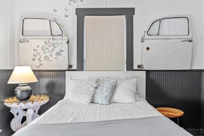 Une chambre à coucher avec un lit, une table de chevet avec une lampe et une fenêtre avec des volets.