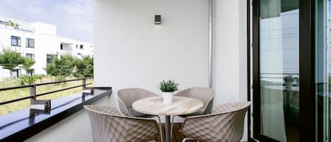 Un balcón con mesa y sillas, una planta en maceta y vistas a edificios.