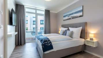 Quarto de hotel moderno com uma cama grande, televisão, varanda e um quadro na parede.