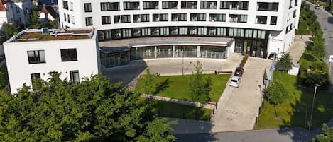 Un edificio de varios pisos con un patio central, rodeado de árboles y un estacionamiento.