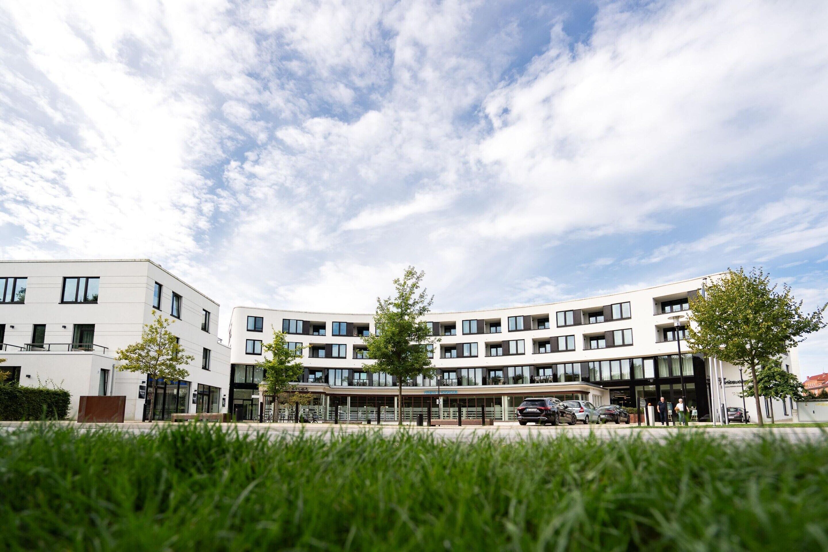Een modern gebouw met meerdere verdiepingen, grote ramen en een plat dak.