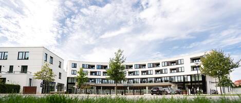 Een modern gebouw met meerdere verdiepingen, grote ramen en een plat dak.