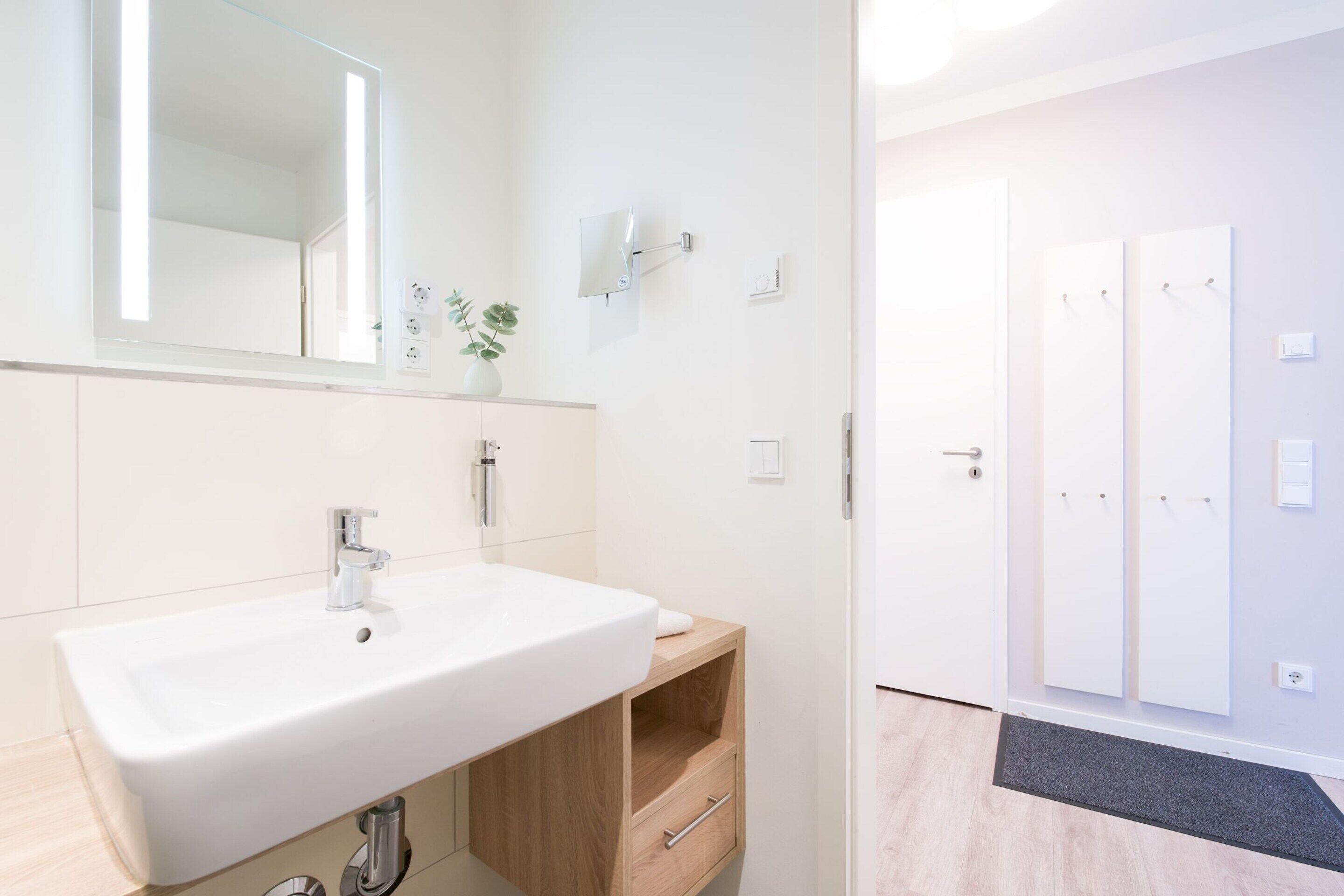 Un baño moderno con un lavamanos grande, un espejo y una planta en maceta.