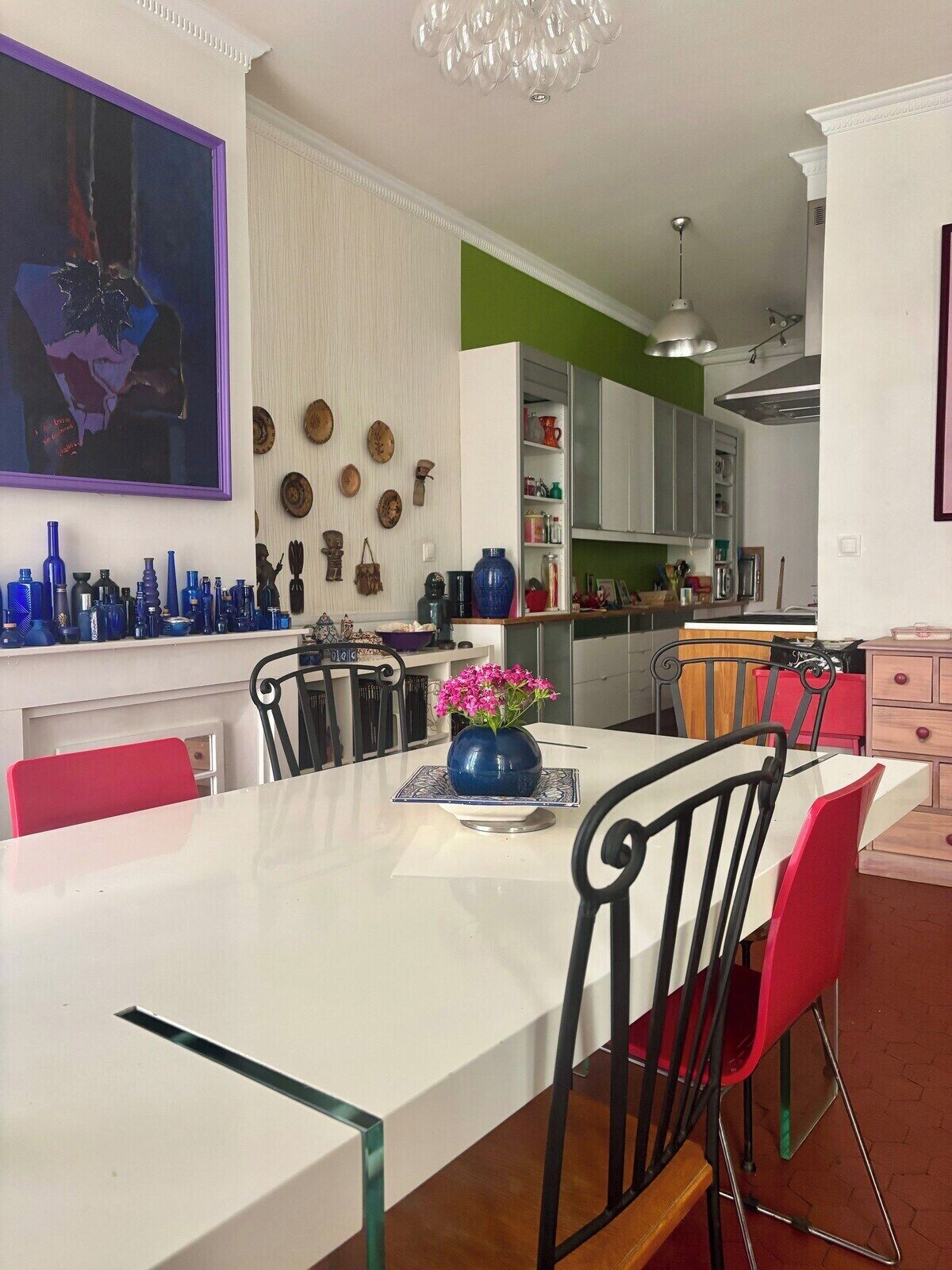 Une cuisine moderne avec des meubles blancs, une table à manger avec des chaises et un lustre.