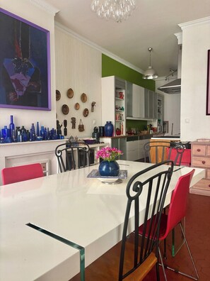 Una cocina moderna con armarios blancos, una mesa de comedor con sillas y una araña.