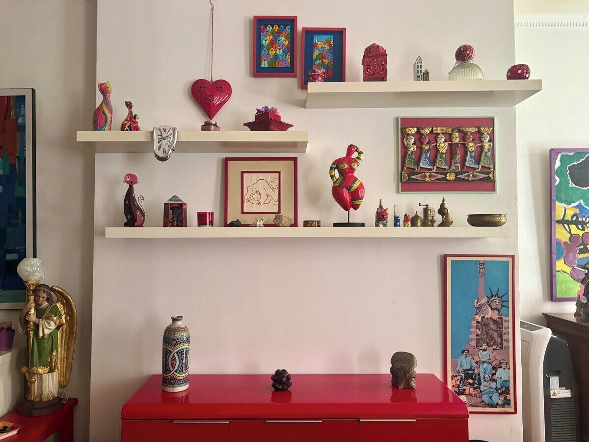 Una stanza con un armadio rosso, mensole con diversi oggetti decorativi e un quadro raffigurante la Statua della Libertà.