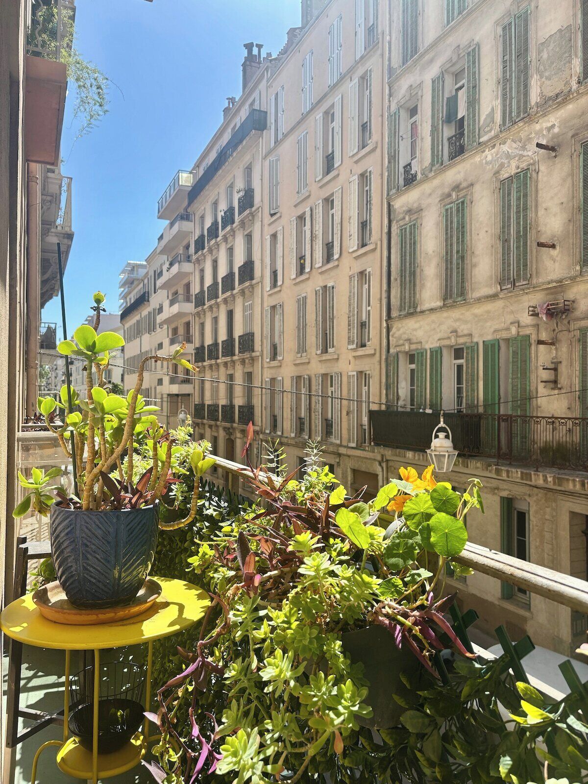 Un balcone con un vaso di fiori e un tavolino.