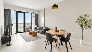 Ein modernes Wohnzimmer mit Essbereich, großen Fenstern und Blick auf die Stadt.