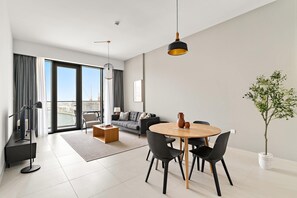 A modern living room with a dining area, large windows, and a view of the city. - Silkhaus Canal Side 2bdr Apartment in Al Wasl (Dubai)