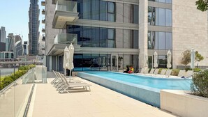 Ein modernes Gebäude mit Poolbereich auf dem Dach, inklusive Liegestühlen und Sonnenschirmen.