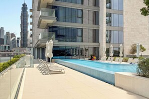 A modern building with a rooftop pool area, including lounge chairs and umbrellas. - Silkhaus Canal Side 2bdr Apartment in Al Wasl (Dubai)